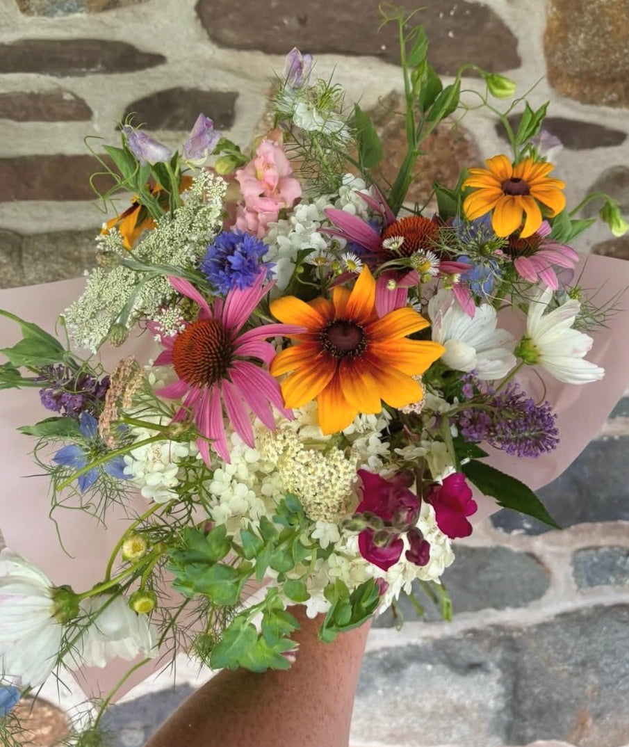Bouquet of colorful flowers held against a stone wall